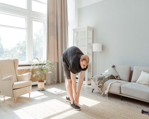 Person doing light morning stretches by a bright window